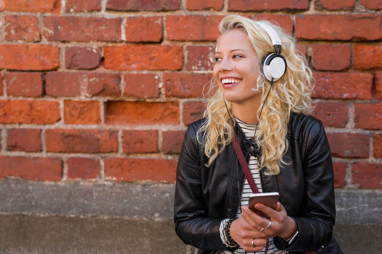 teen listening to music on an iphone against a wall in Australia