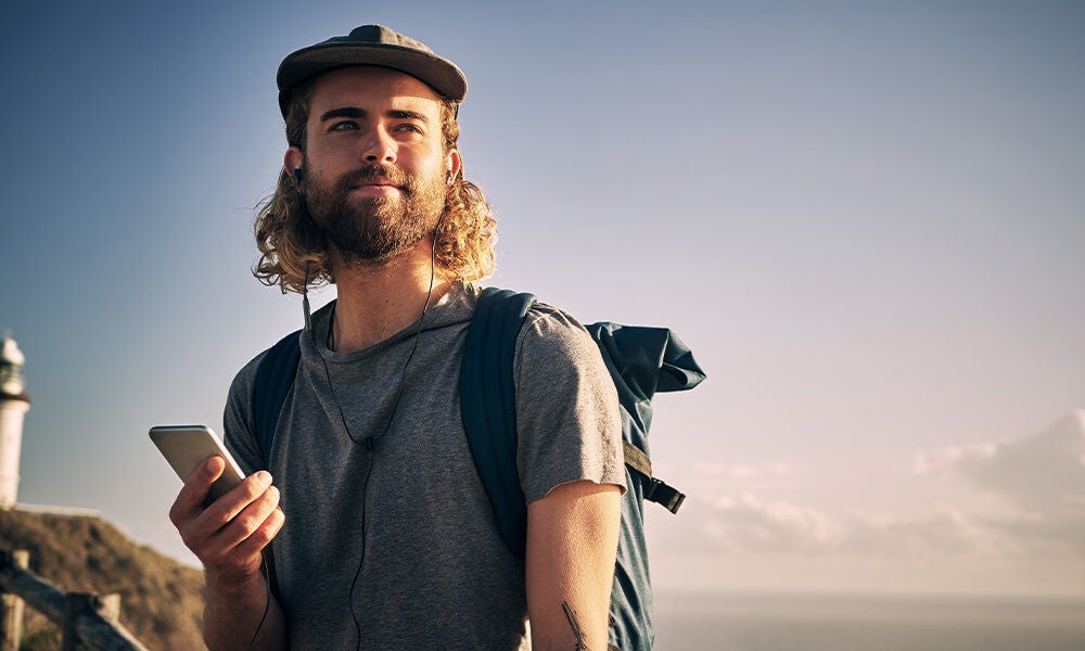 Guy with backpack using his phone outside